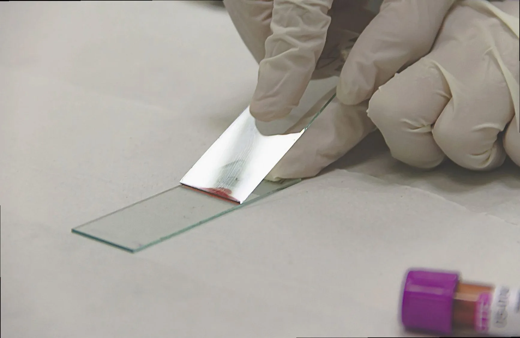 Gloved hand placing a glass slide