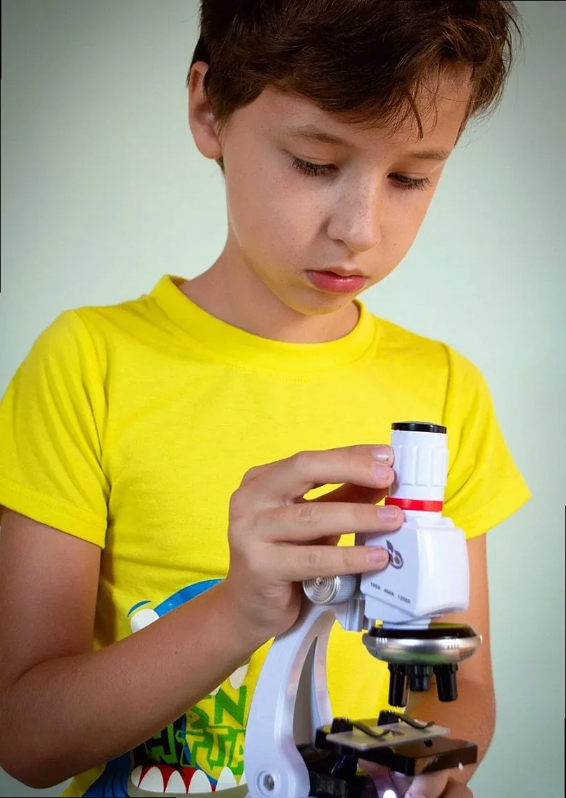 Boy using a microscope in a yellow shirt